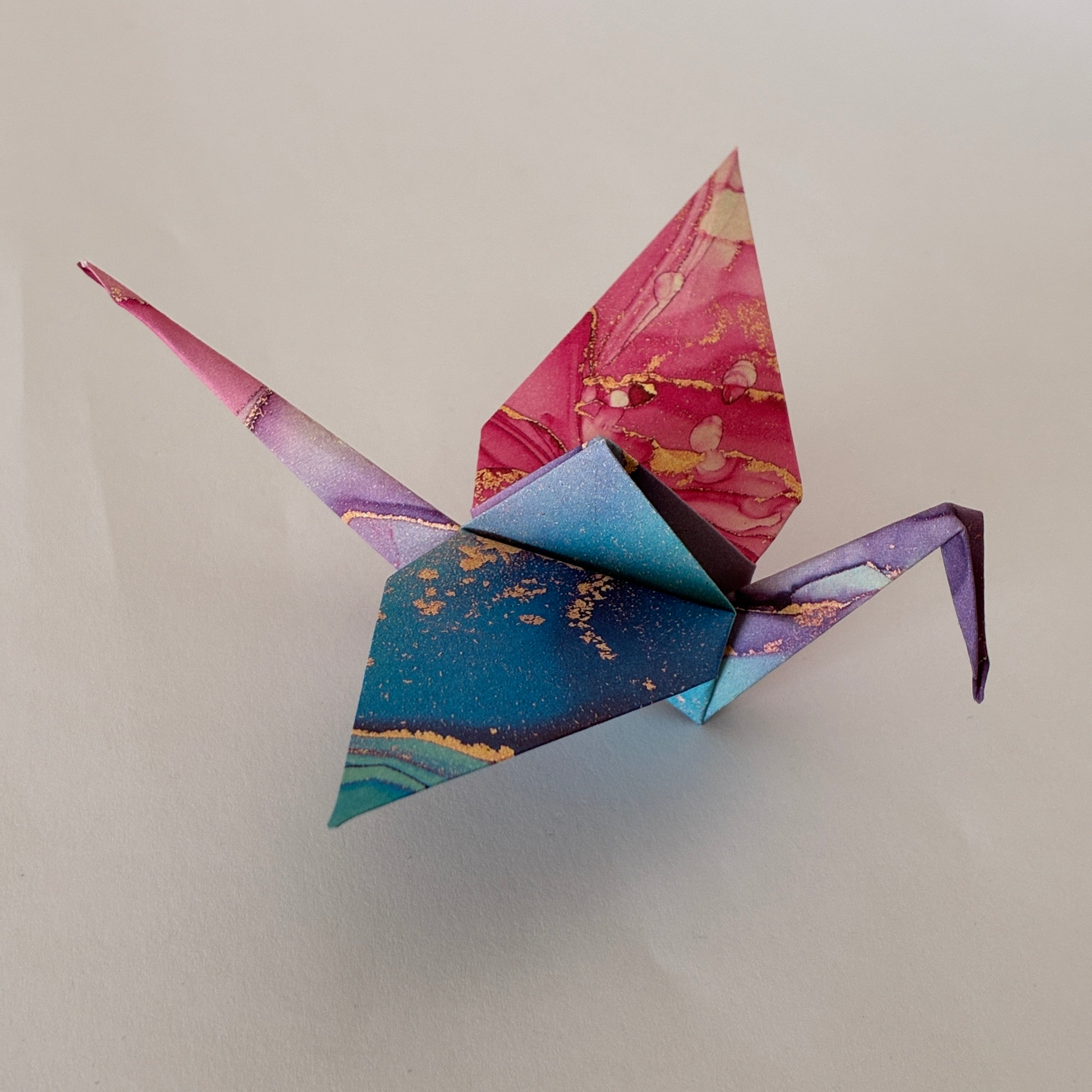 Grue origami (orizuru) en papier marbré rose et bleu, pliée à la main - Suisse