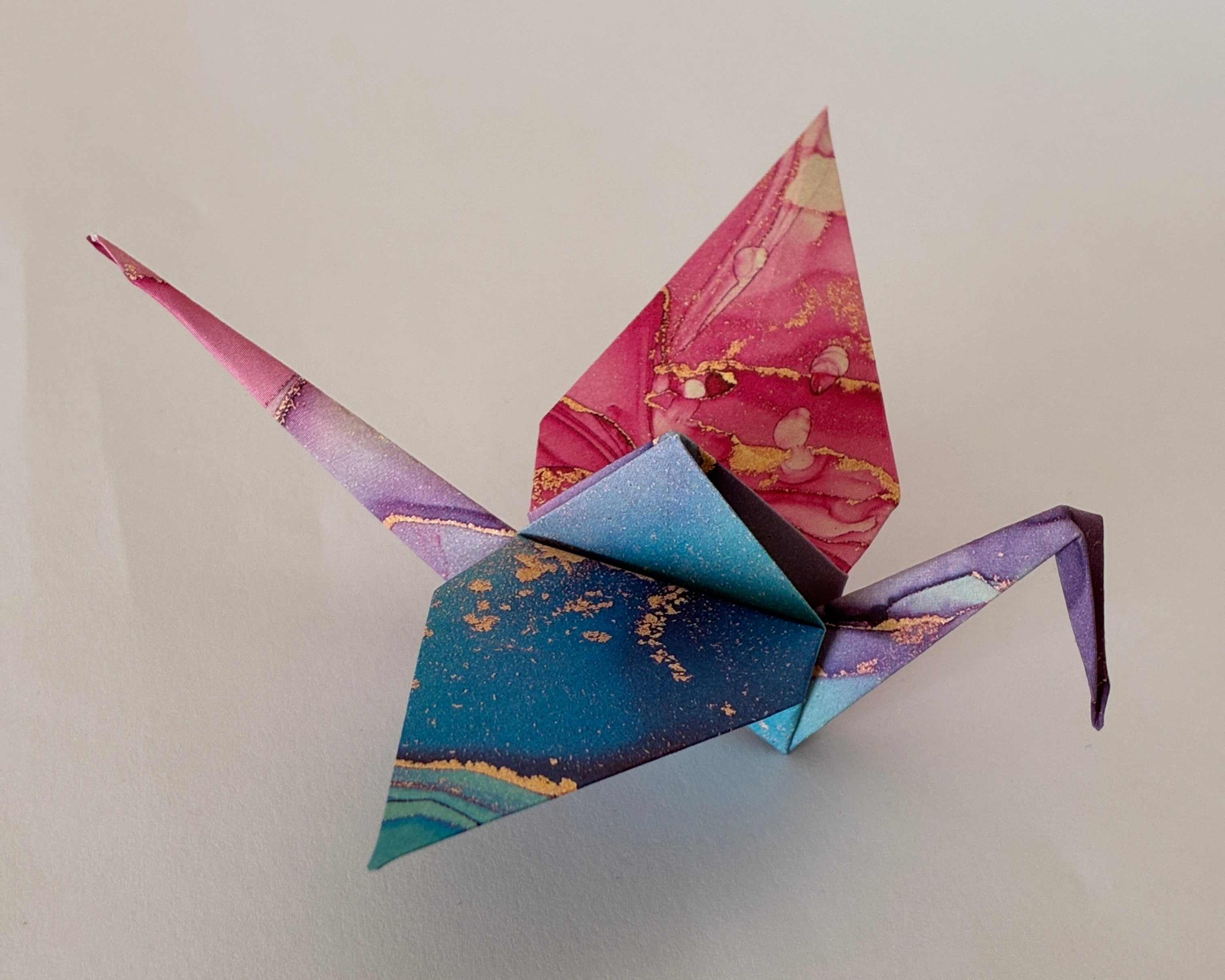 Grue origami (orizuru) en papier marbré rose et bleu, pliée à la main - Suisse