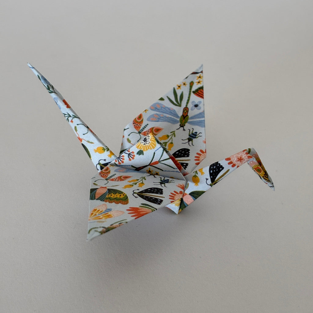 Grue origami à motifs fleurs et insectes sur papier blanc, pliage japonais - orizuru