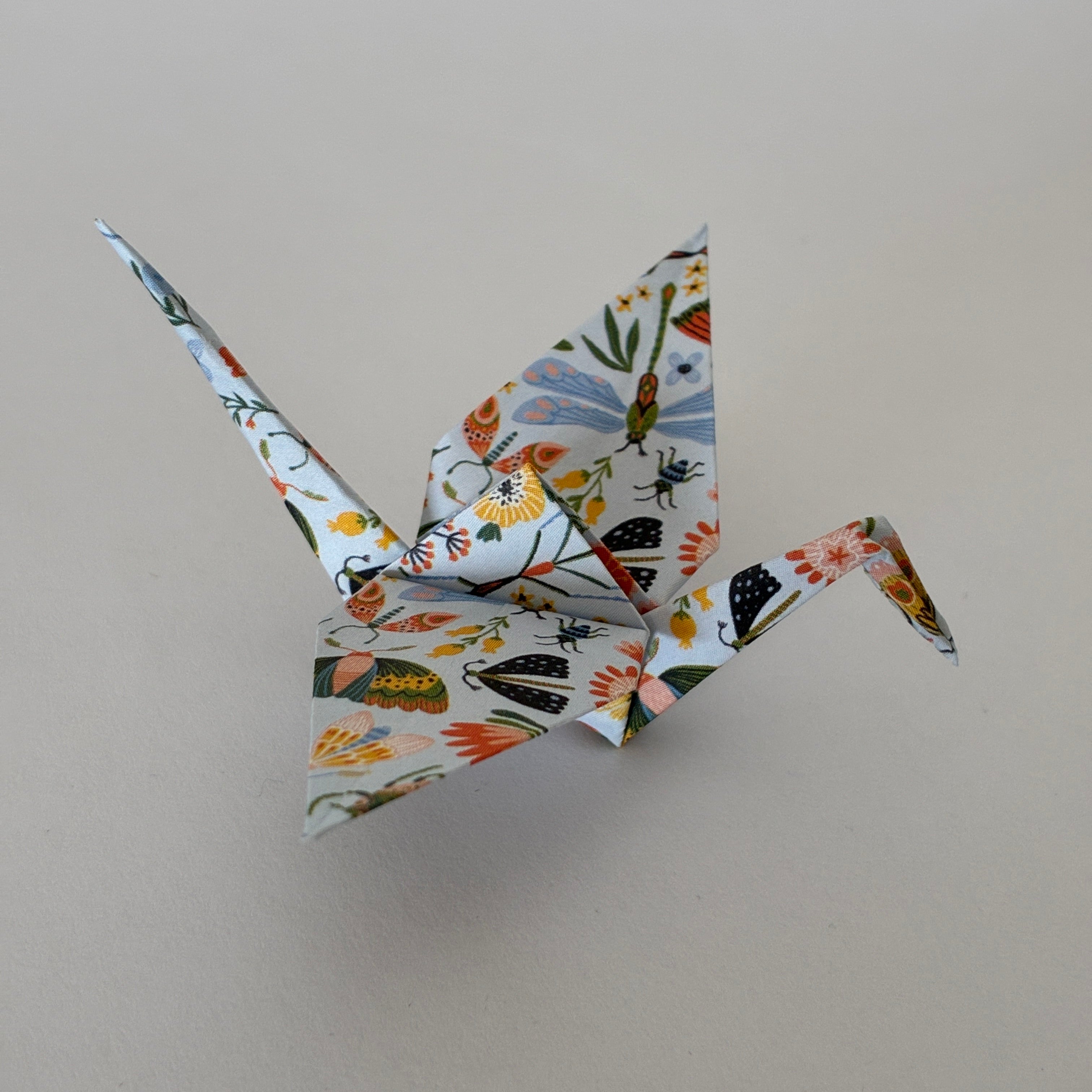 Grue origami à motifs fleurs et insectes sur papier blanc, pliage japonais - orizuru